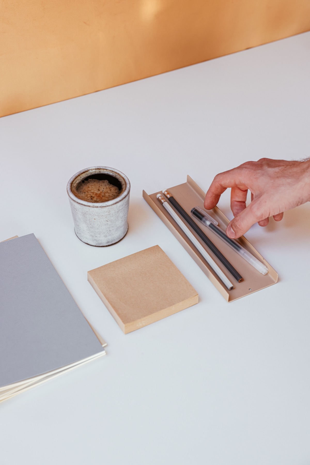 Hand arranging pencils on a tidy white desk